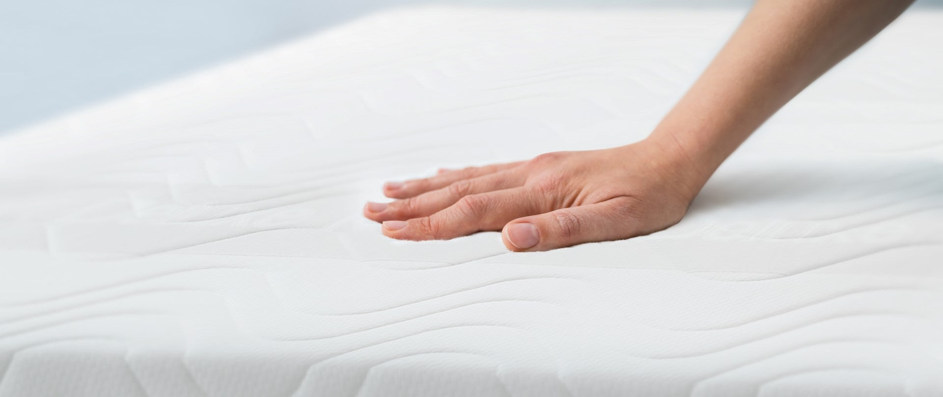 Image of a hand touching a mattress